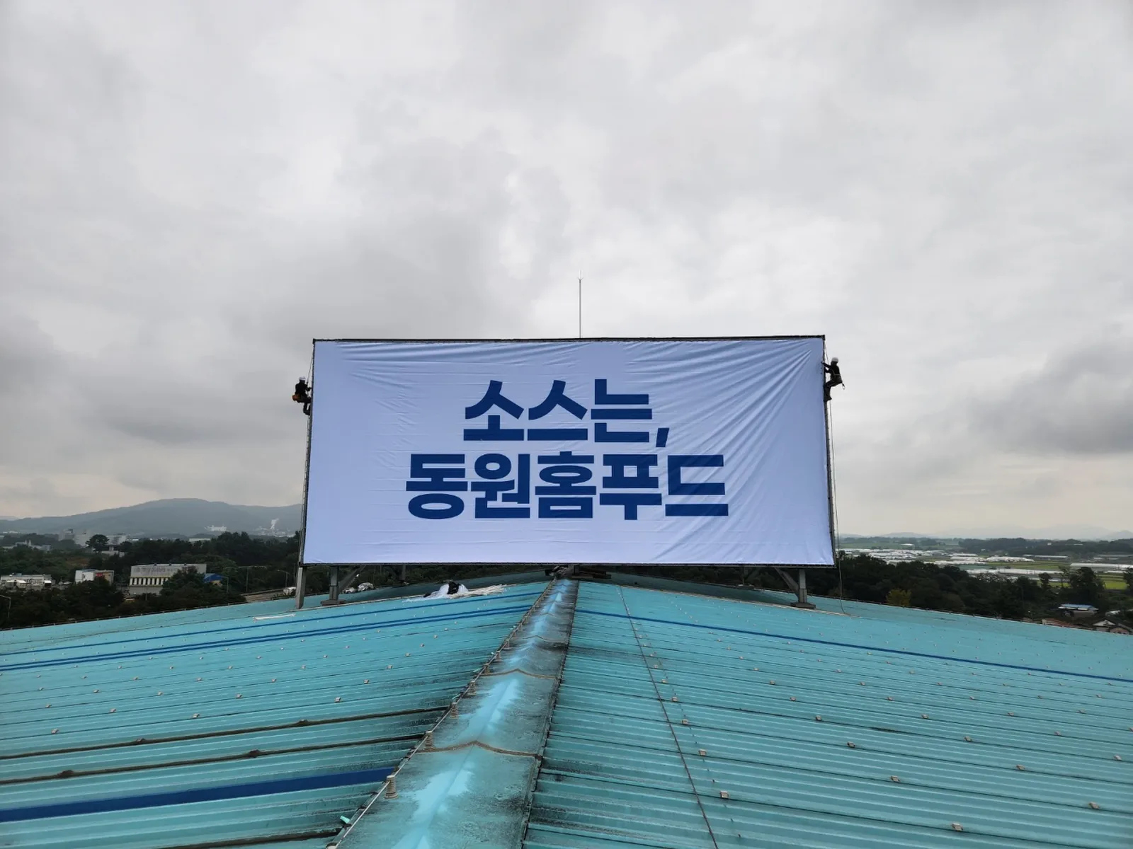 옥상광고탑 배접 화면 설치가 끝난 뒤 양옆에서 마감 작업 중인 로프 작업자들