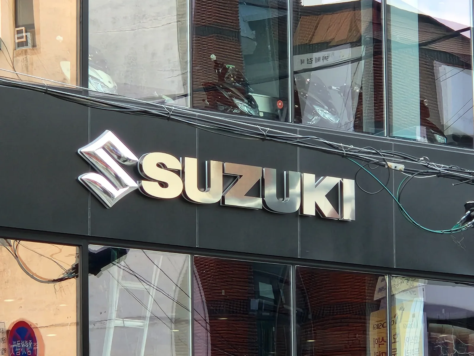 쇼룸 건물 외벽에 부착된 SUZUKI 로고와 문자 채널사인 근접 사진