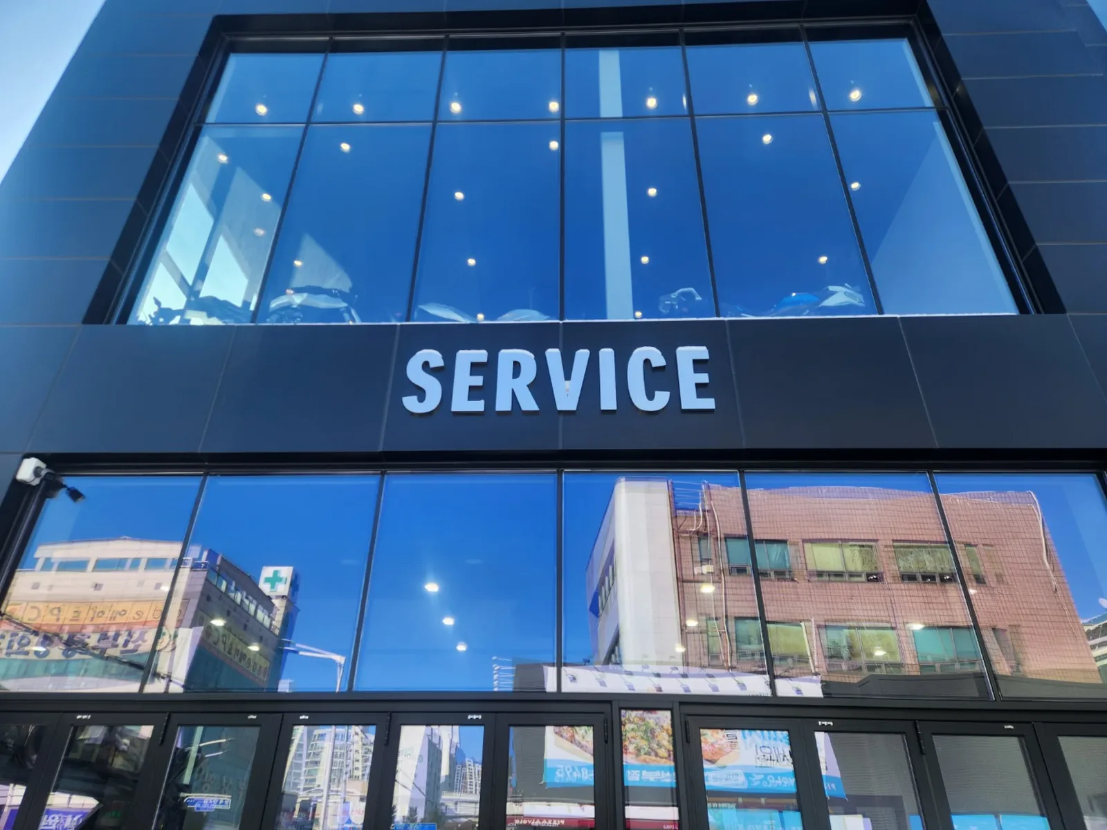 쇼룸 건물 2층 파사드에 부착된 SERVICE 라이트박스형 간판 글자, 통유리창 배경